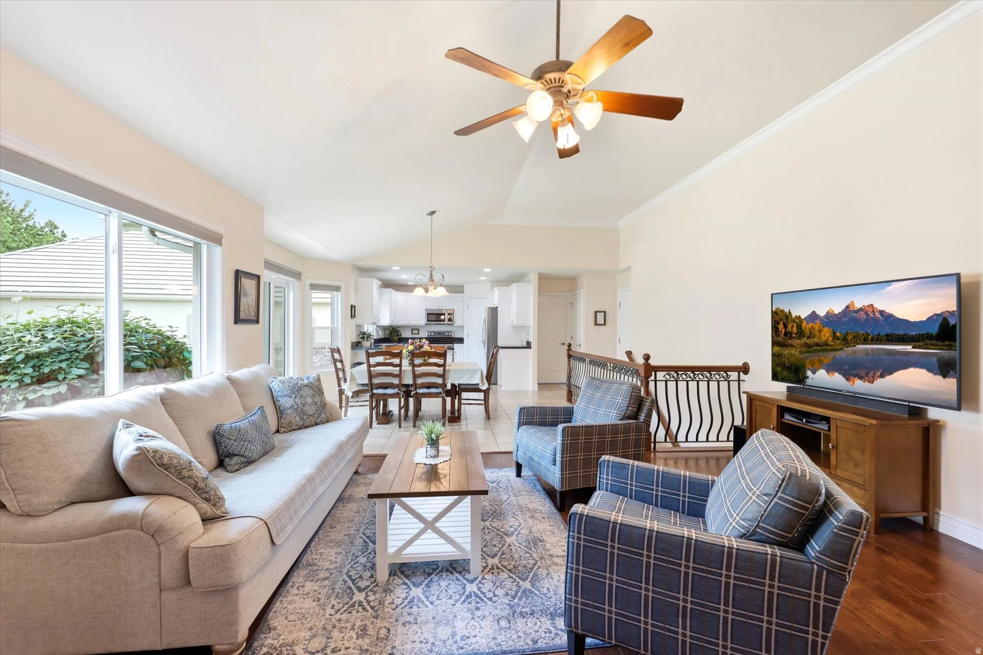Vaulted ceiling living space featuring rich wood-finish flooring, large windows, and an open-concept dining area