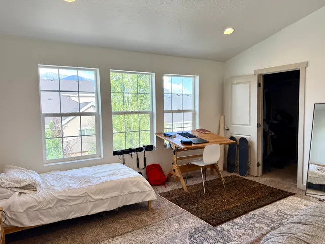 Room featuring three double-hung windows, vaulted ceiling, and recessed lighting