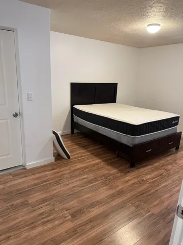 Room featuring wood-finish flooring, white walls, and a flush-mount ceiling light fixture