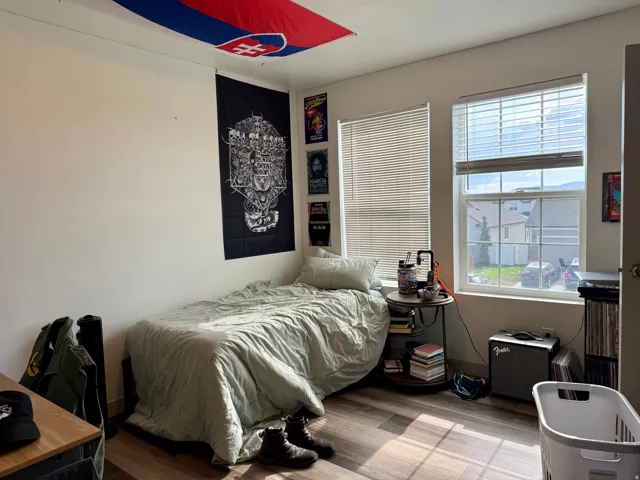 Room featuring two windows with horizontal blinds, wood-finish flooring, and white walls