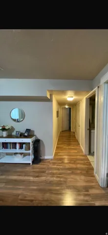 Hallway featuring wood-finish flooring, white trim, and ceiling-mounted lighting fixtures