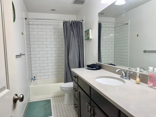 Bathroom featuring a dark wood-finish vanity with a light-toned countertop, an integrated sink, and chrome fixtures