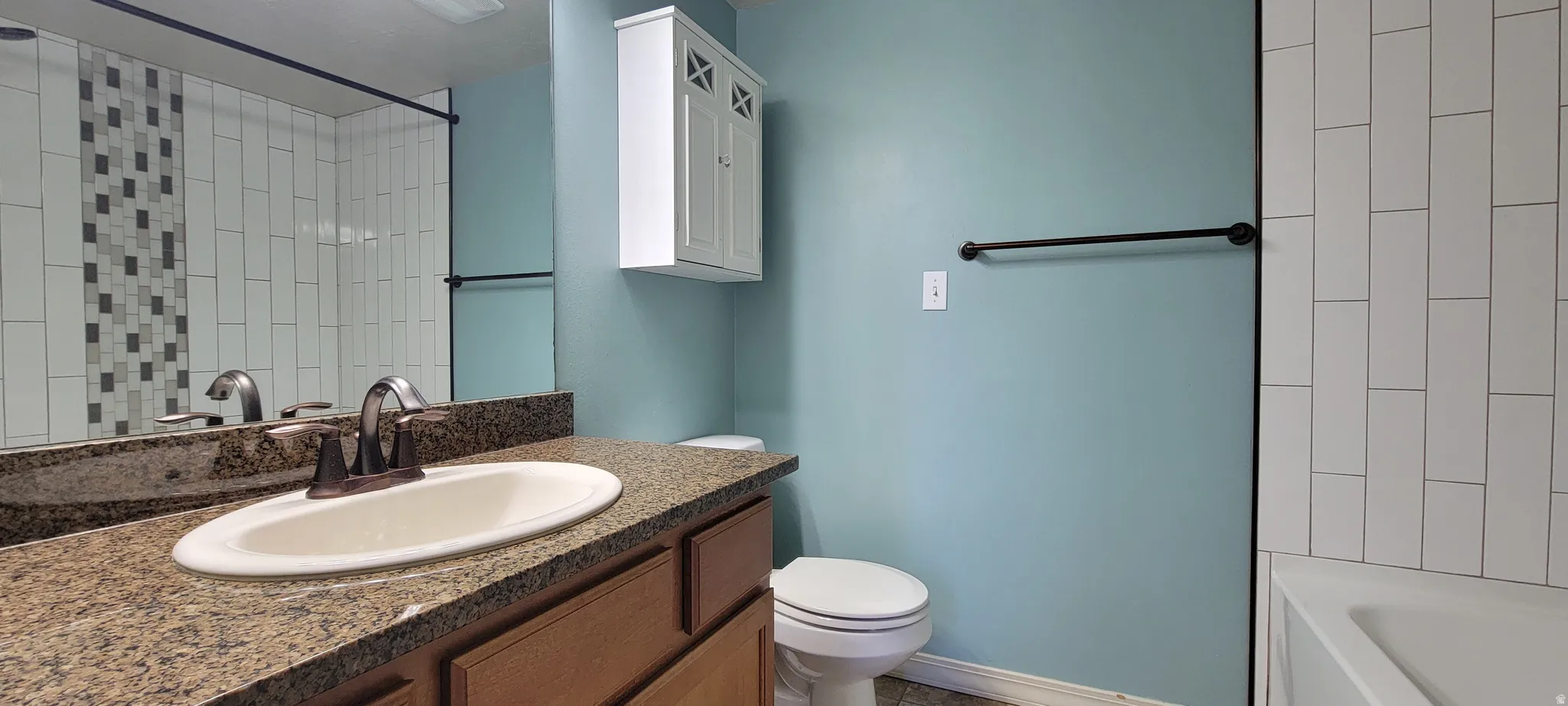 Bathroom featuring a vanity with an integrated sink, a speckled countertop, and wood-finish cabinetry