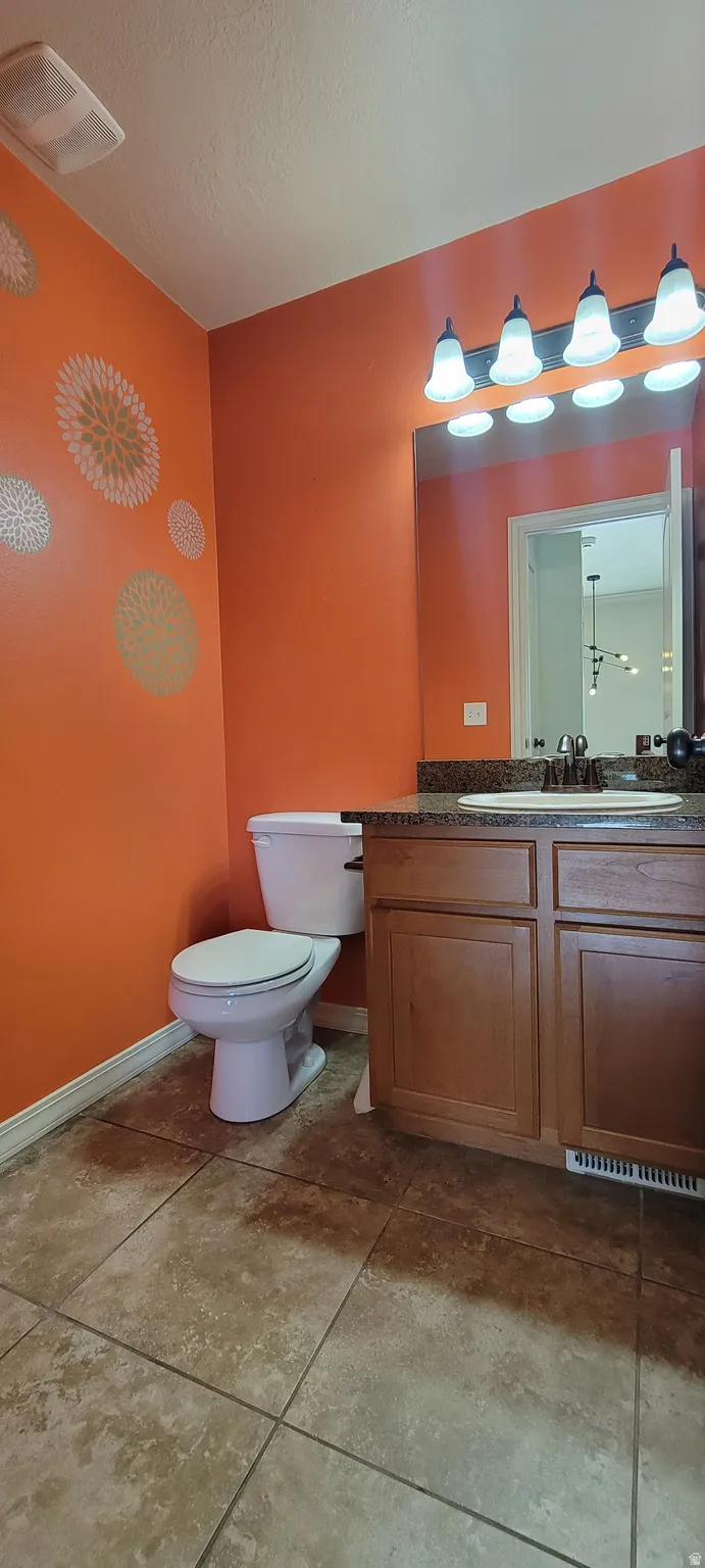 Bathroom featuring a single vanity with wood-finish cabinetry, a white basin sink, and a dark countertop