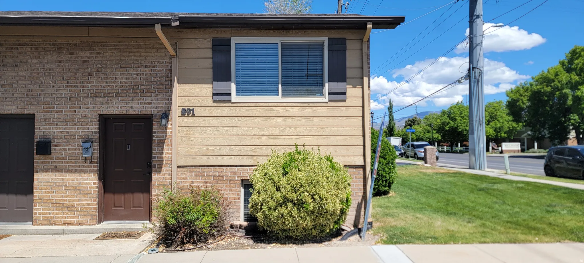 Exterior facade featuring brick and horizontal siding, with a dark brown entry door and coordinating garage door
