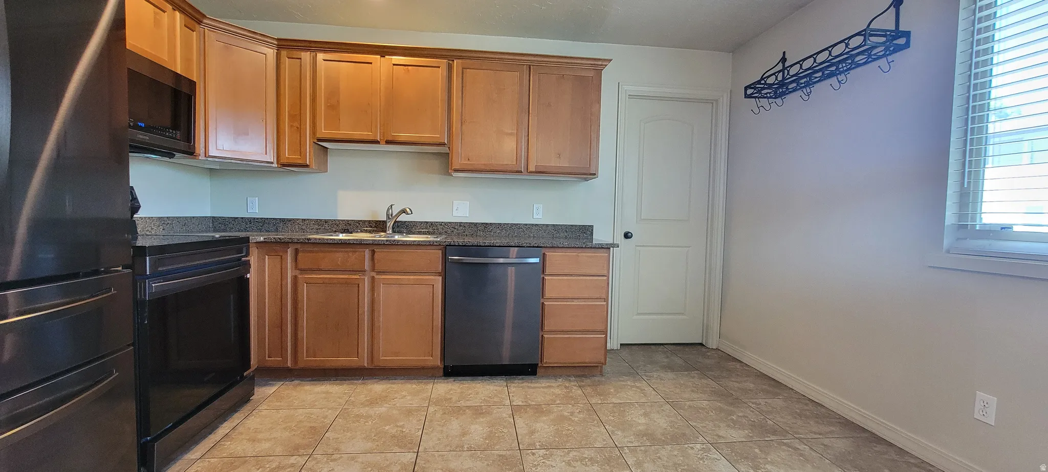 Kitchen featuring light wood cabinetry, stone-finish countertops, stainless steel appliances, and tiled flooring
