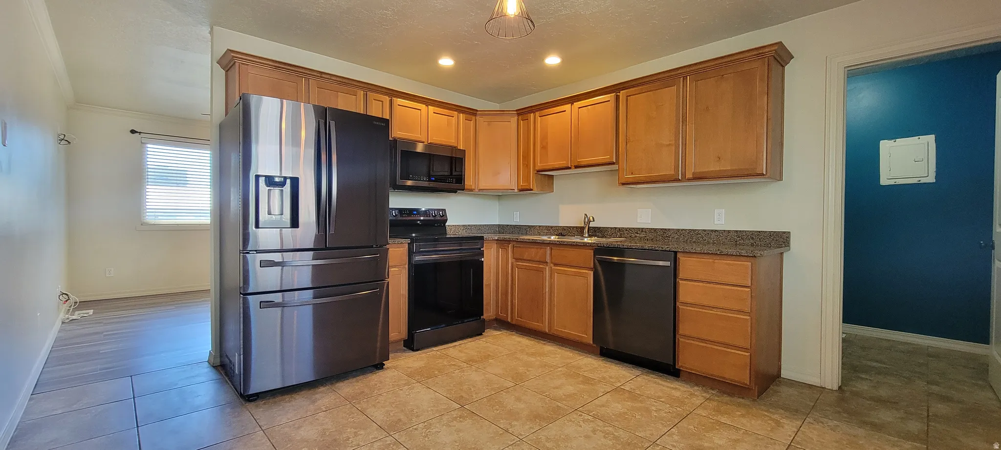 Kitchen featuring wood cabinetry, stainless steel refrigerator, black range, black dishwasher, and a stone-finish countertop