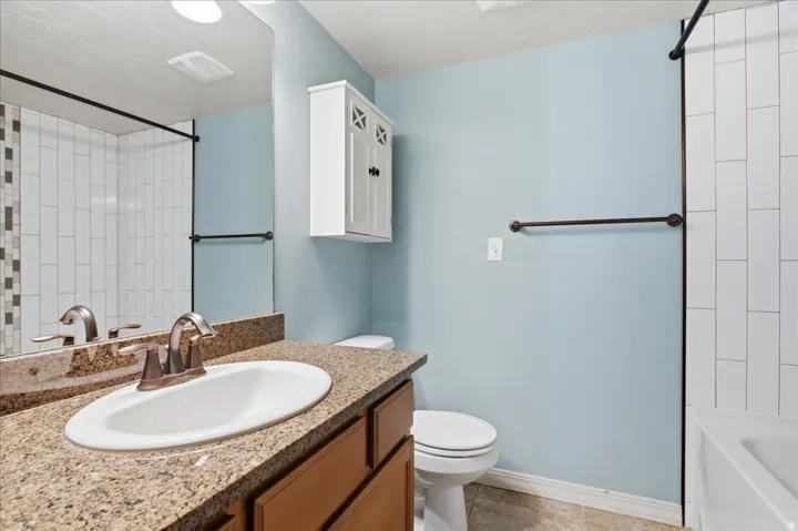 Vanity with a granite countertop, undermount sink, and bronze-finish faucet