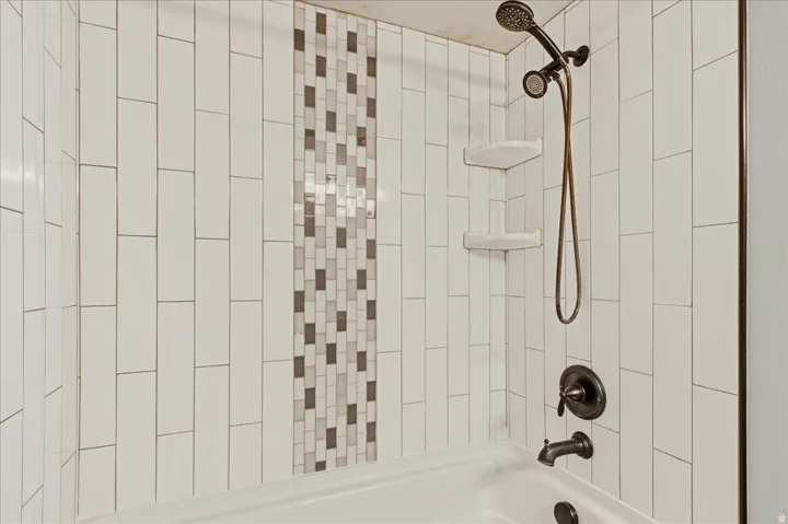 White subway tile shower surround with a mosaic accent strip
