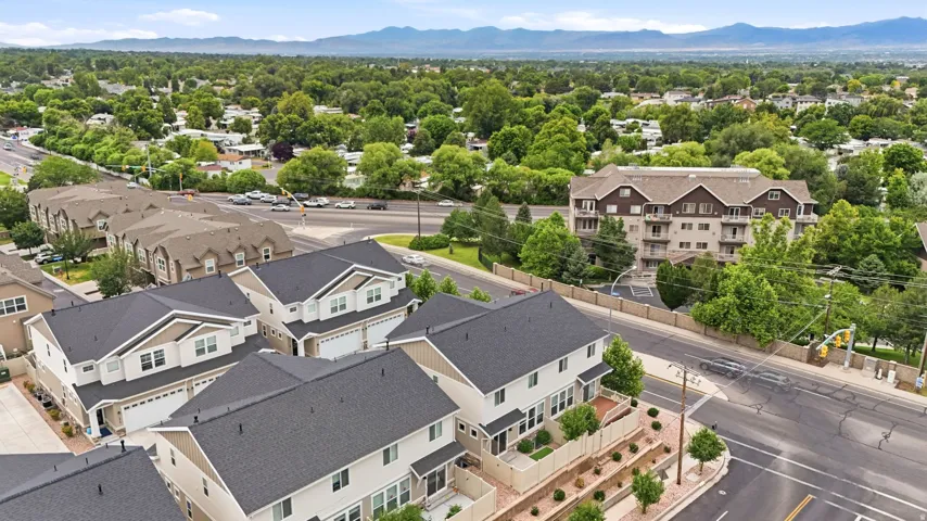 Contemporary townhome development featuring light-toned siding, dark shingle roofing, and attached garages