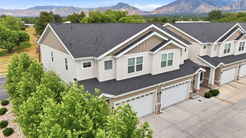 Contemporary townhome exterior featuring light-toned siding, dark shingle roofing, and white trim accents