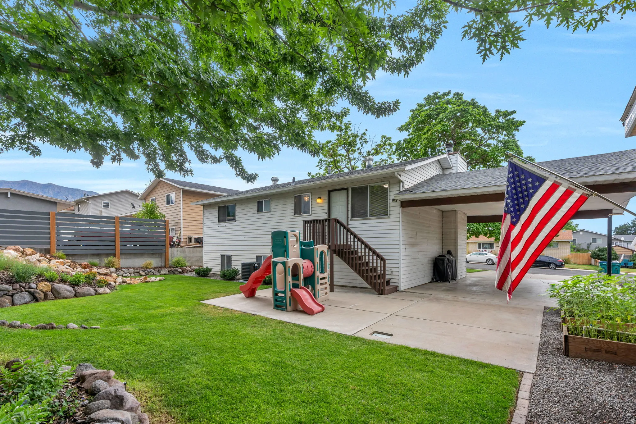 Expansive rear yard featuring a manicured lawn, concrete patio, and mature trees