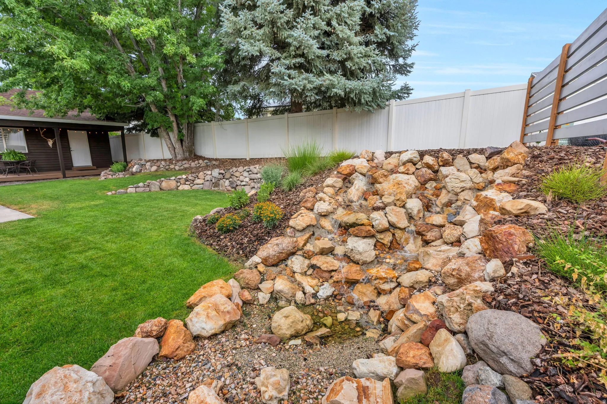 Terraced backyard with rock landscaping and an integrated water feature