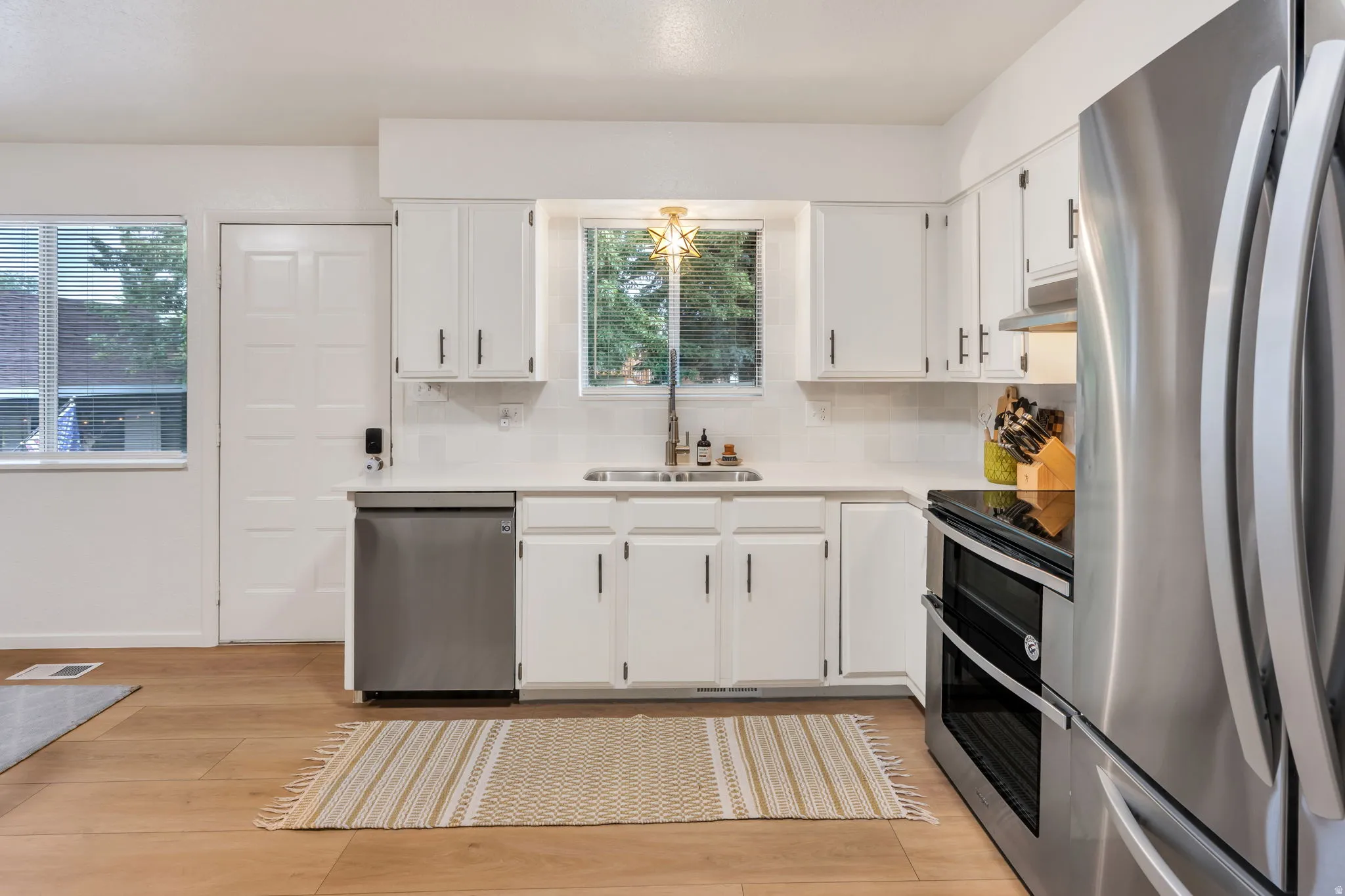 Bright kitchen featuring white cabinetry, light countertops, and wood-finish flooring