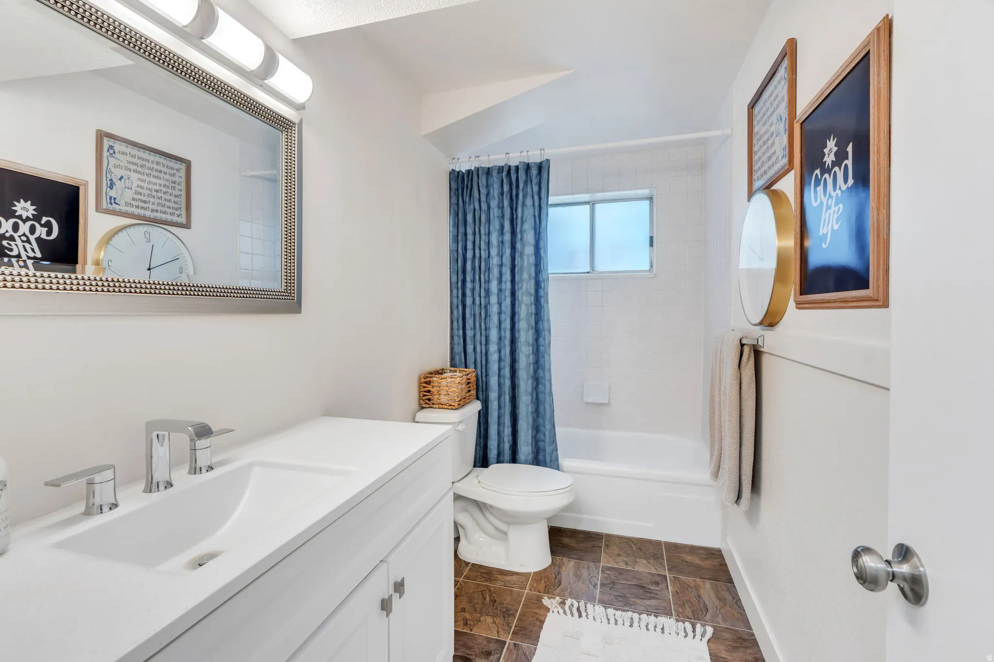 Bathroom featuring a white vanity with an integrated sink and chrome fixtures, a framed mirror, and a white bathtub with a shower
