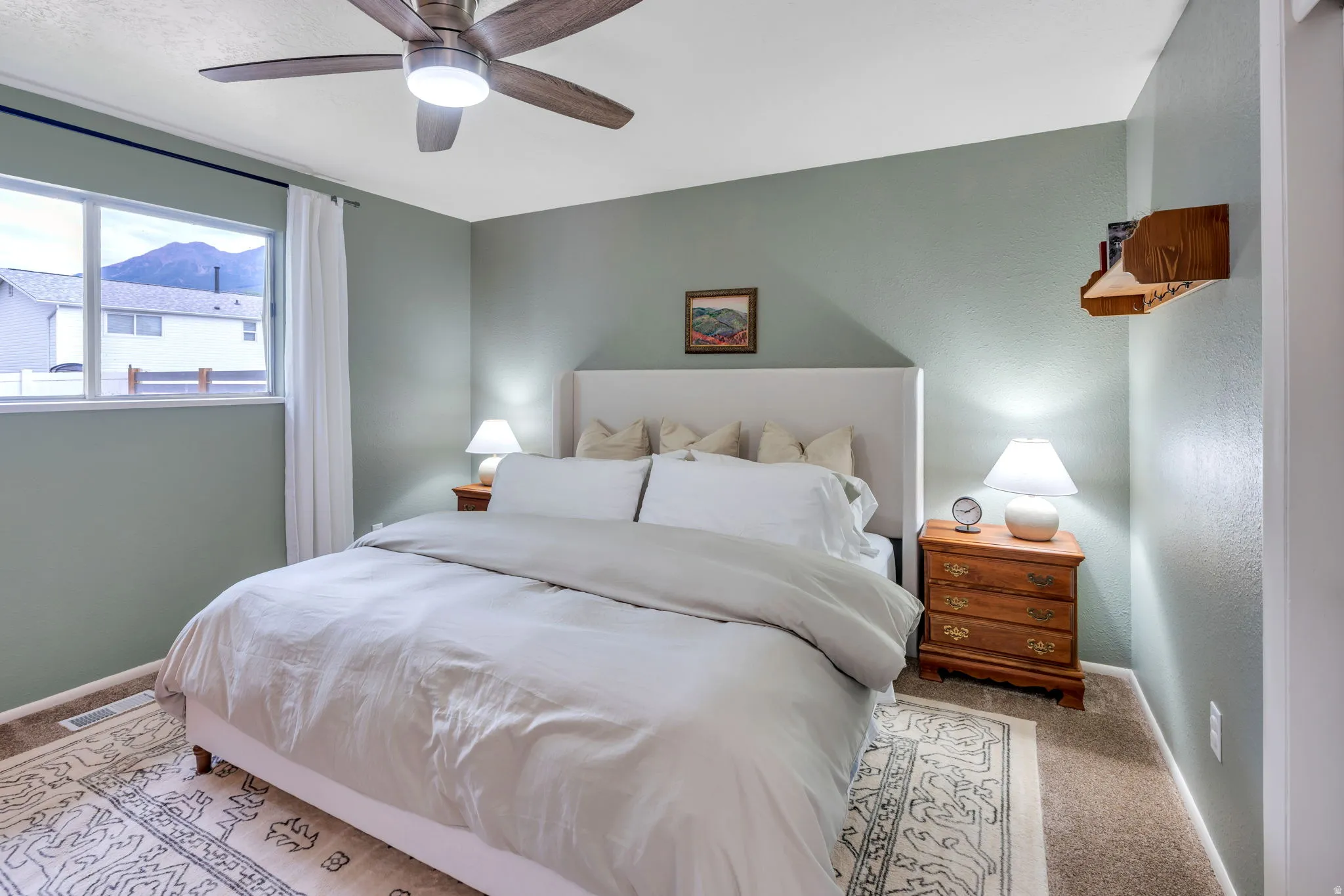 Bedroom featuring a ceiling fan with integrated lighting, a window with mountain scenery, and light-toned walls