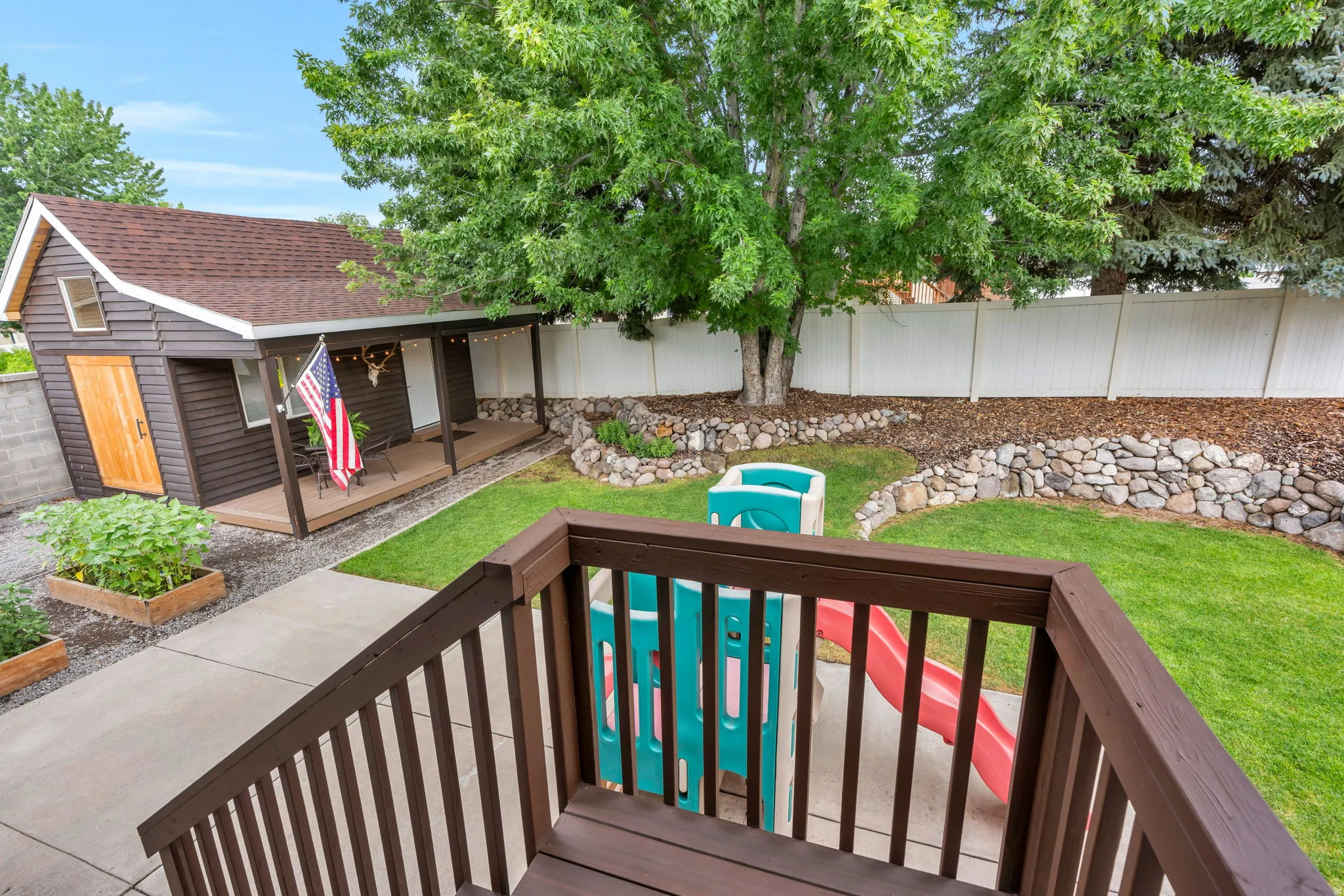 Expansive backyard featuring a manicured lawn, established trees, and a privacy fence
