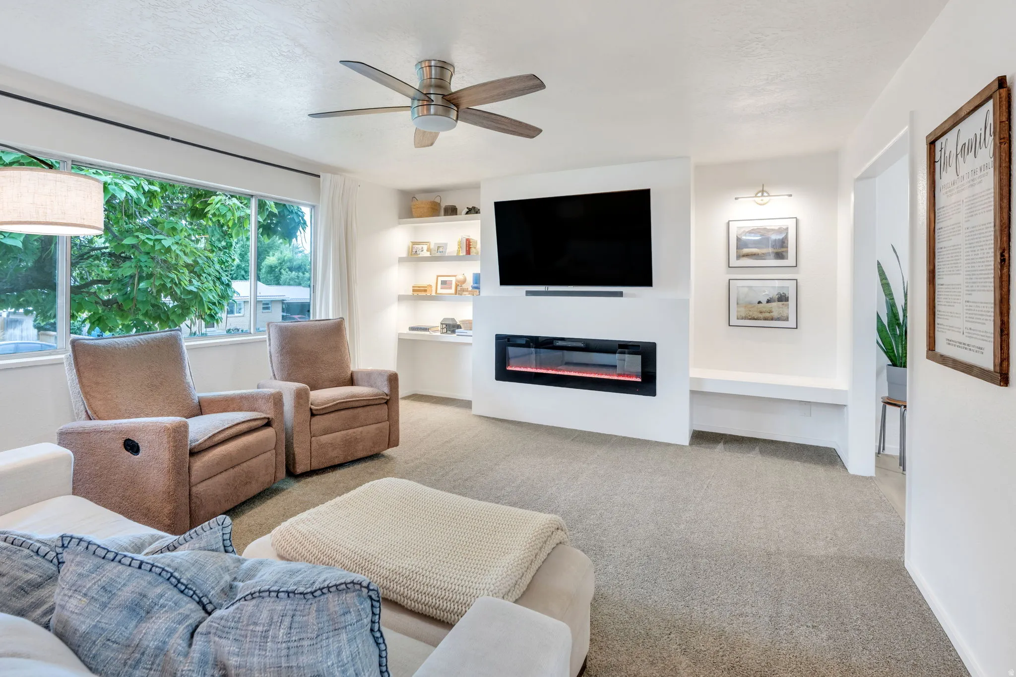 Living area featuring a built-in electric fireplace, integrated shelving with accent lighting, and a ceiling fan