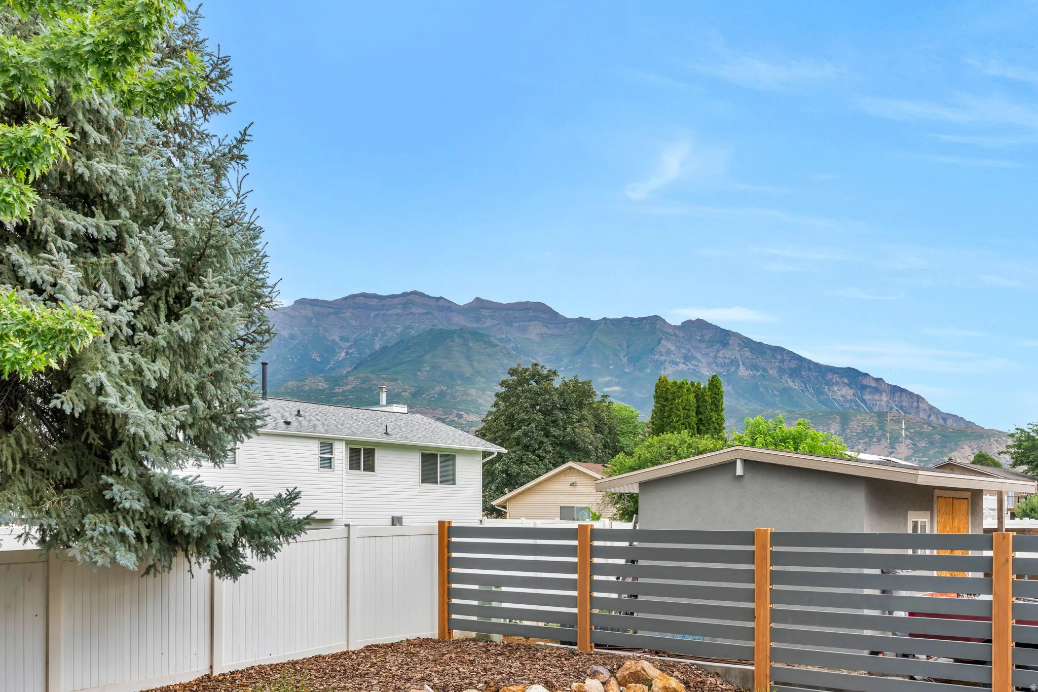 Expansive outdoor space featuring a white privacy fence and a modern slatted fence with natural wood posts