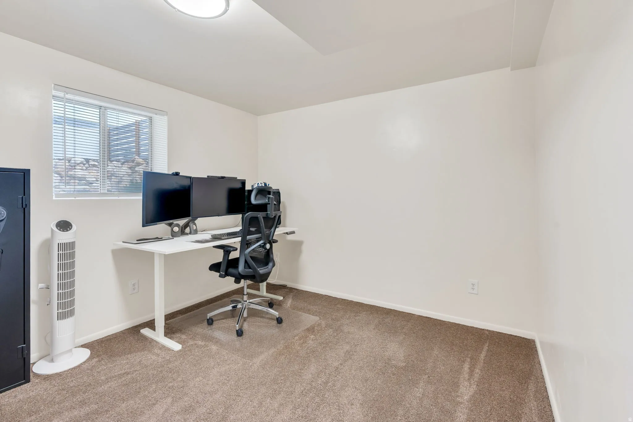 Neutral-toned carpeting and white walls complement a window with horizontal blinds