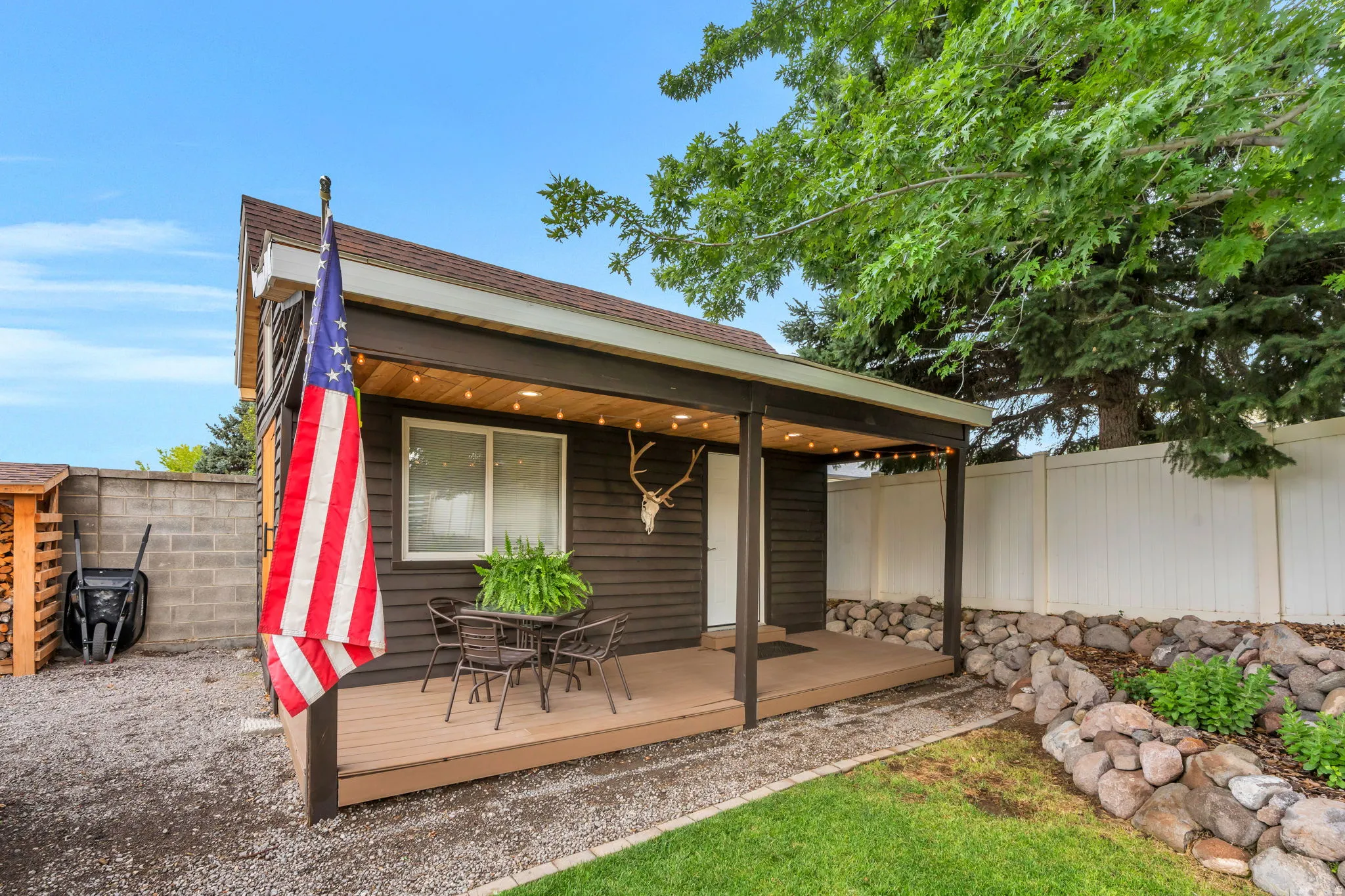 Covered outdoor patio area featuring string lighting, wood-finish decking, and dark siding