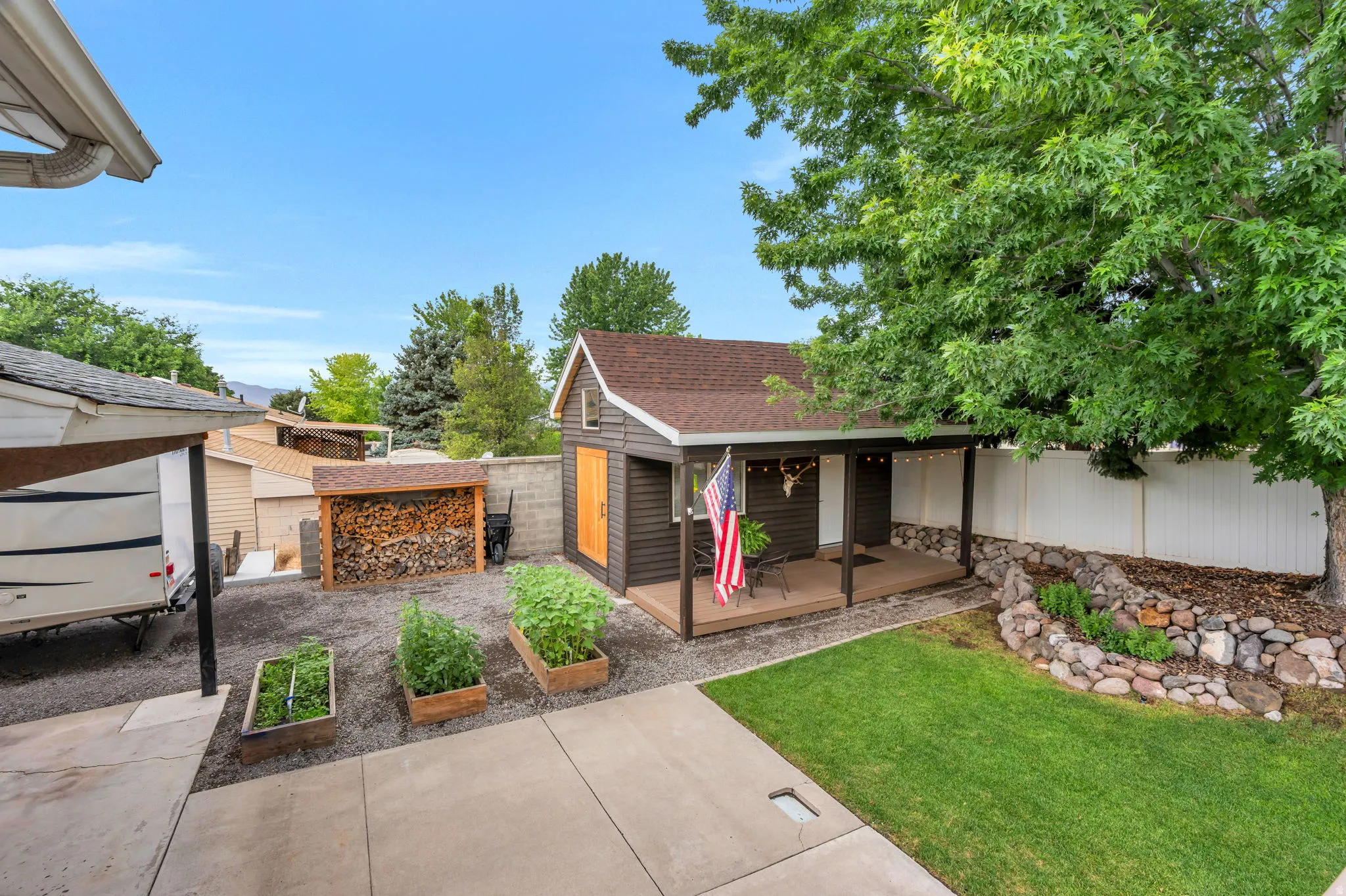 Backyard featuring a detached shed with a covered porch, a manicured lawn, and raised garden beds