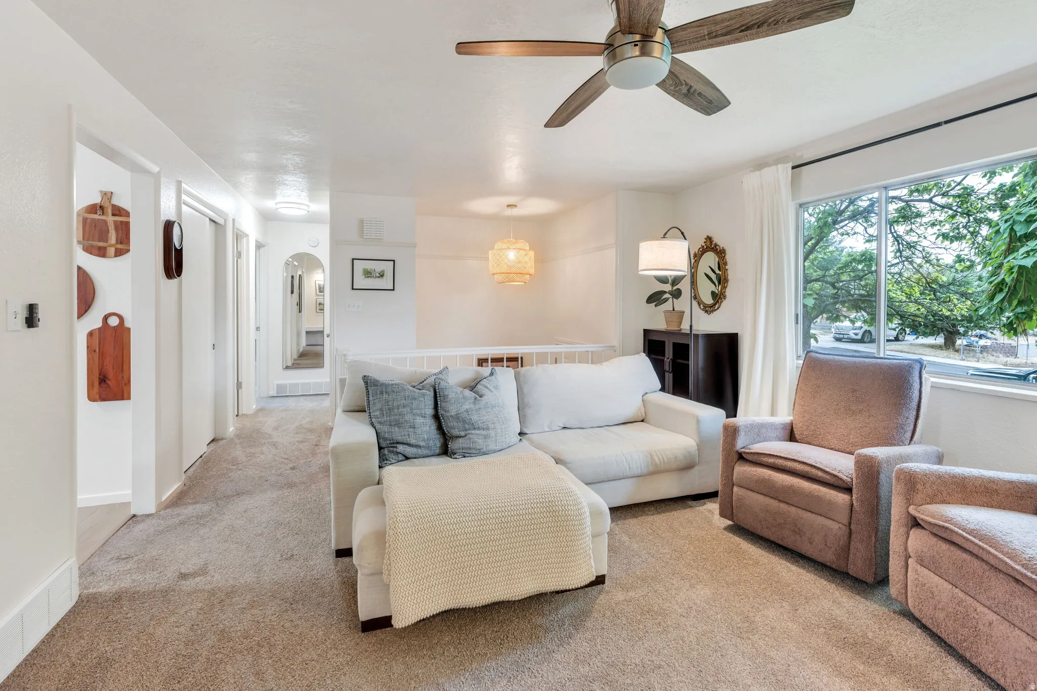 Carpeted living area featuring a large window, a ceiling fan with wood-finish blades, and recessed lighting