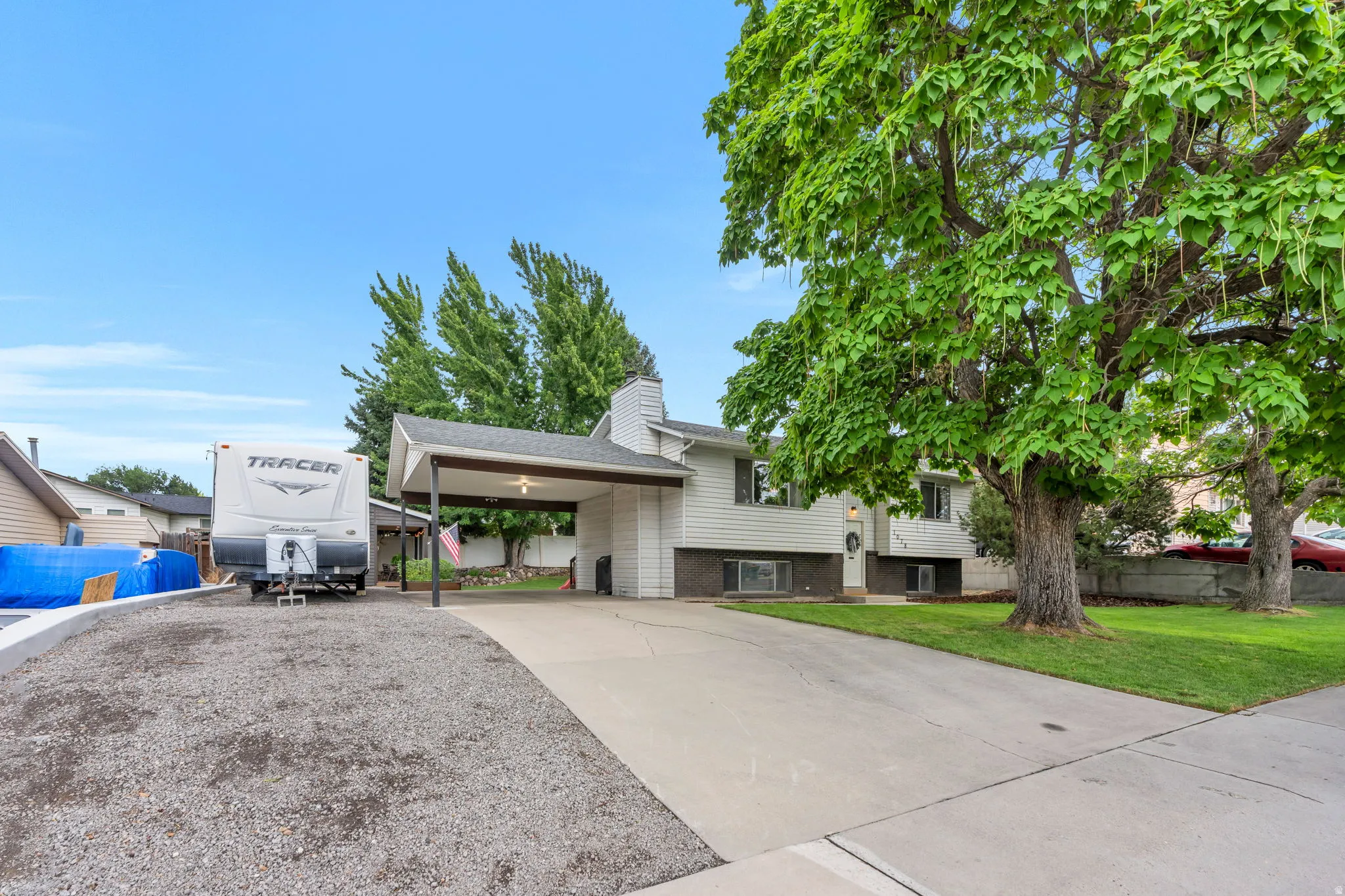 Split-level residence featuring white siding and a covered carport