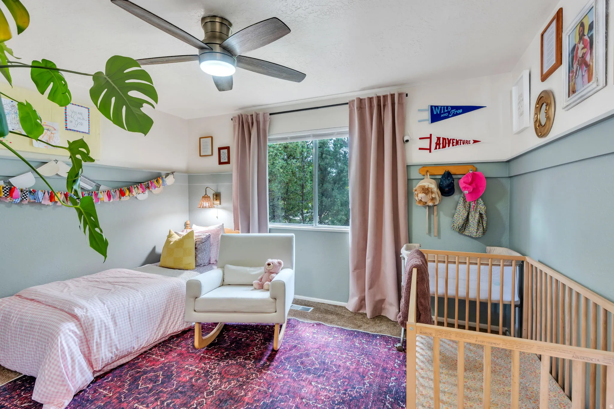 Room featuring a ceiling fan with integrated lighting, a window with pink drapes, and a wall-mounted sconce