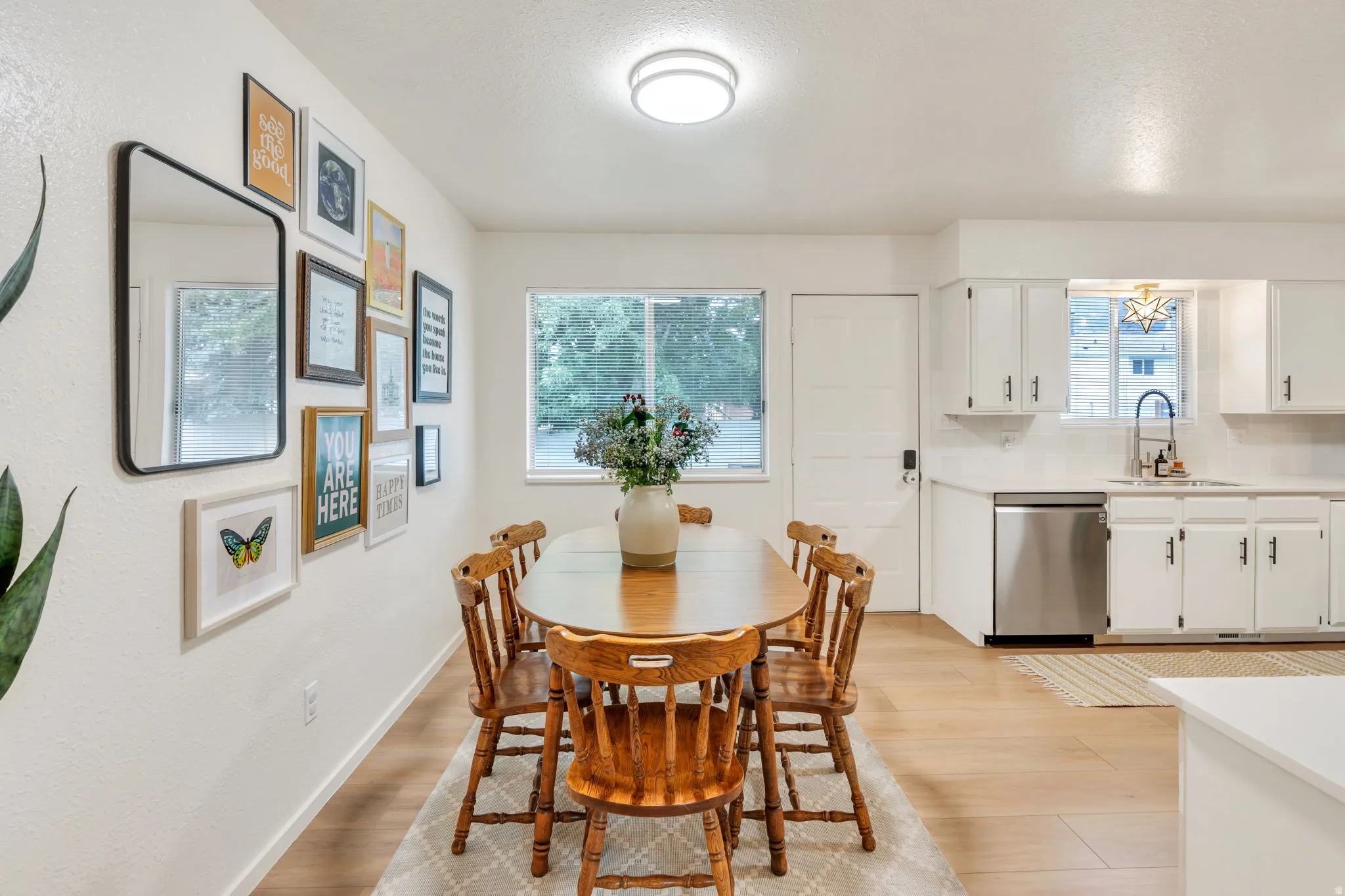 Open-concept dining area featuring light wood-finish flooring, white walls, and a large window