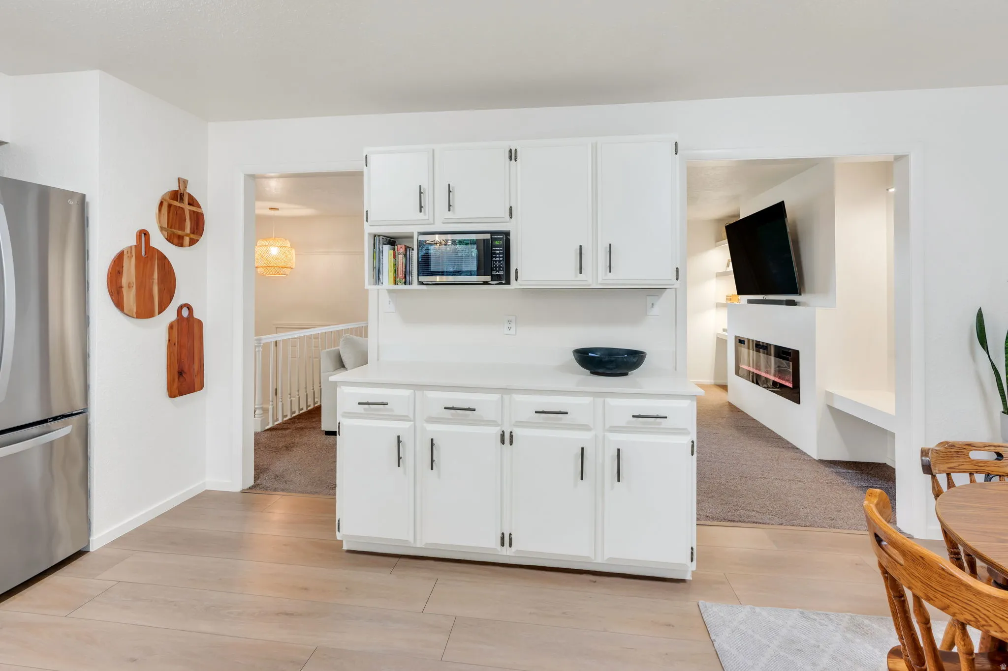 Kitchenette with white cabinetry, built-in microwave, and stainless steel refrigerator