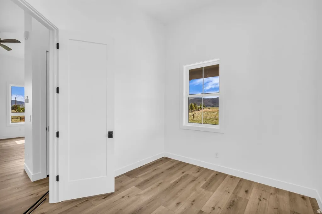 Bright room featuring wood-finish flooring, white walls, and a single window offering a scenic landscape