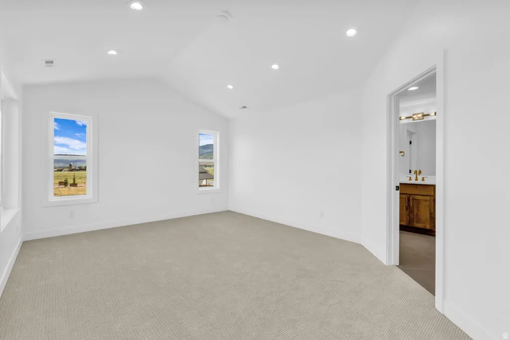 Carpeted room with vaulted ceilings and recessed lighting