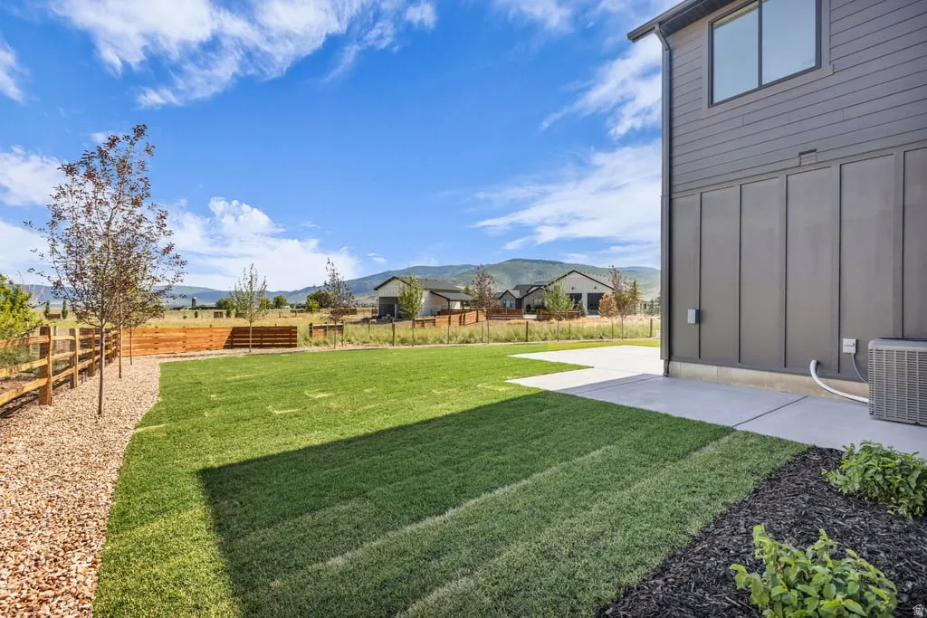 Spacious backyard featuring a manicured lawn, concrete patio, and a wood-slat fence