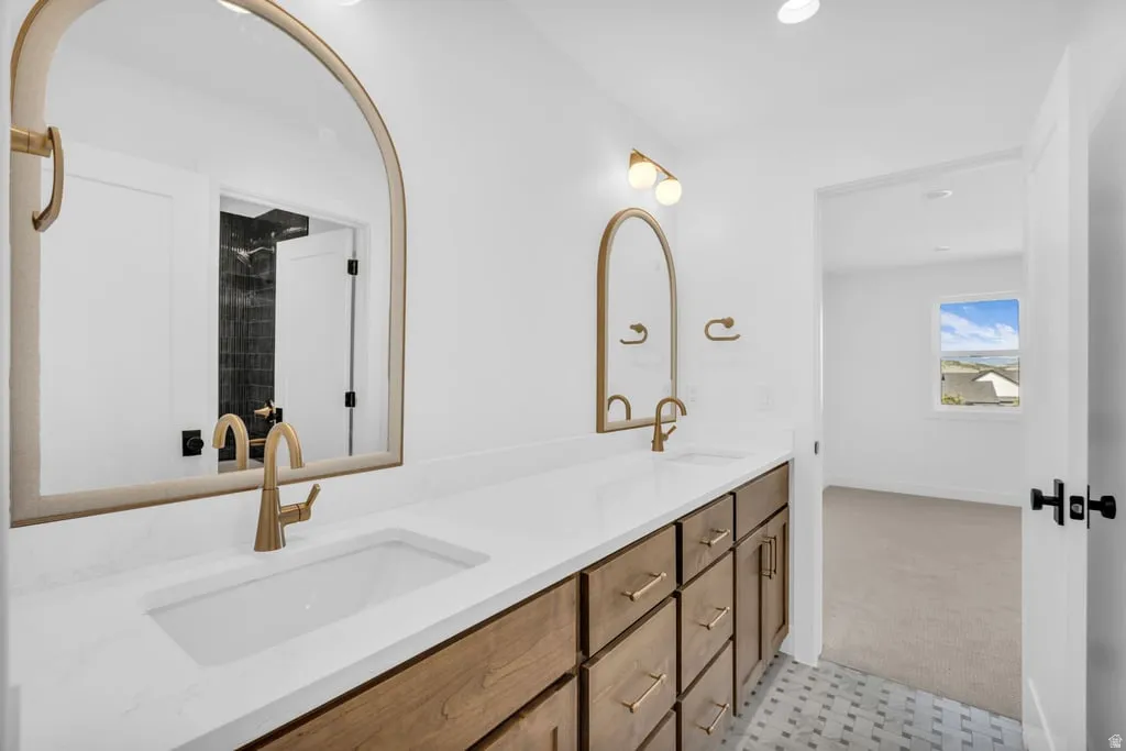 Dual vanity featuring a wood-finish cabinet, white countertop, integrated sinks, and brass fixtures