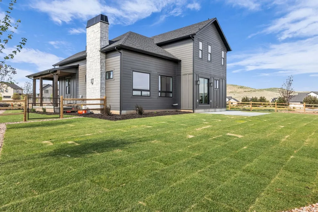 Contemporary two-story exterior with dark siding and a prominent stone-clad chimney