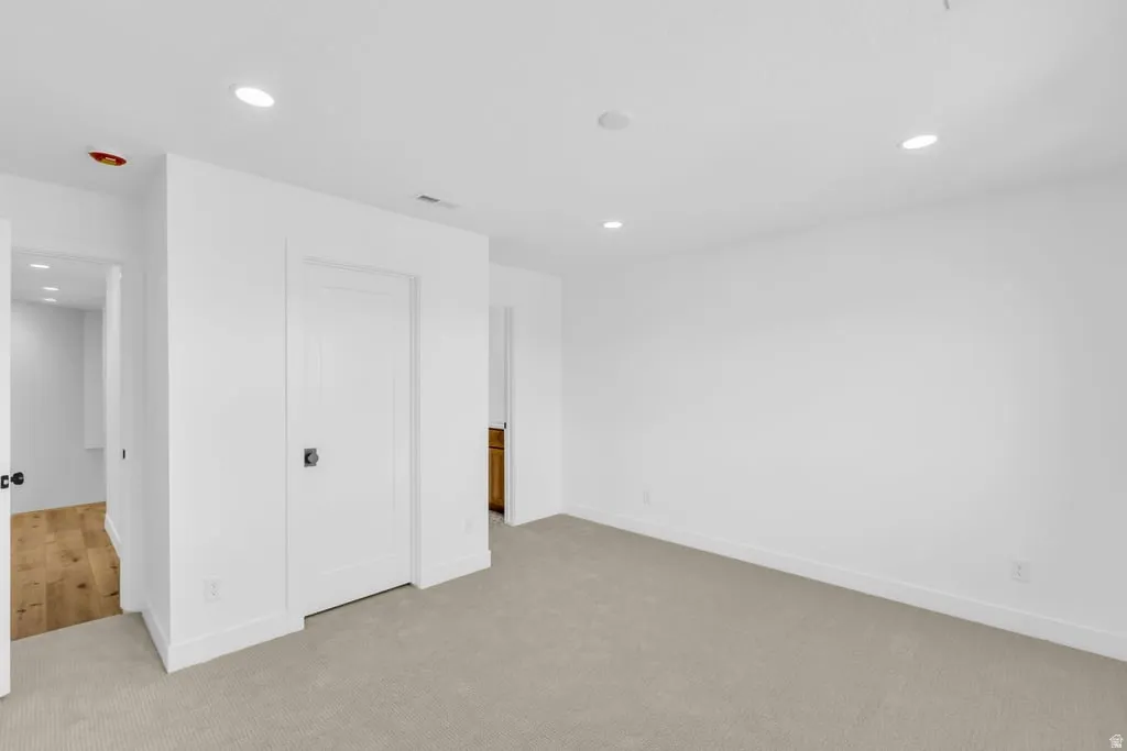 Carpeted room with recessed lighting and crisp white walls