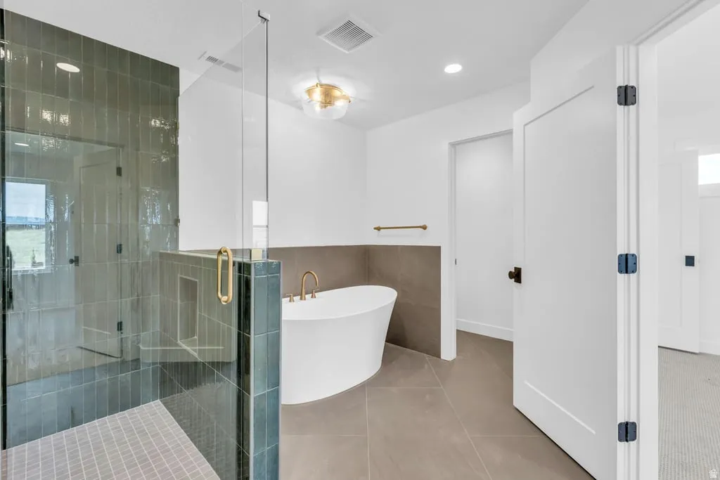 Spacious bathroom featuring a glass-enclosed shower with vertical tile, a freestanding soaking tub, and large format floor tiling