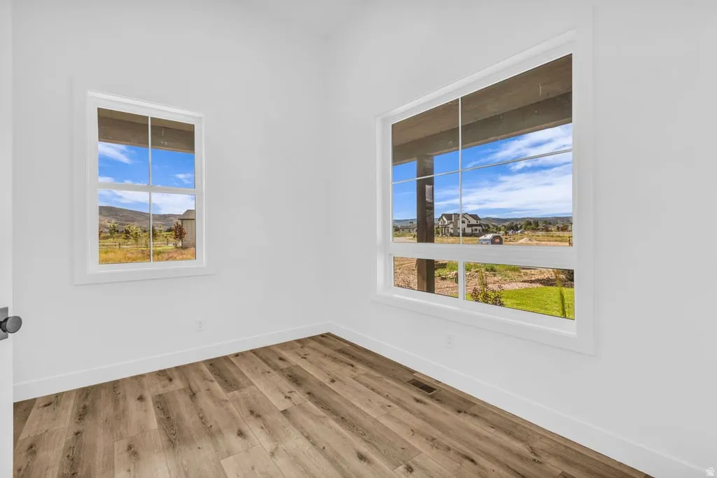 Bright room featuring two large windows, wood-finish flooring, white walls, and white trim