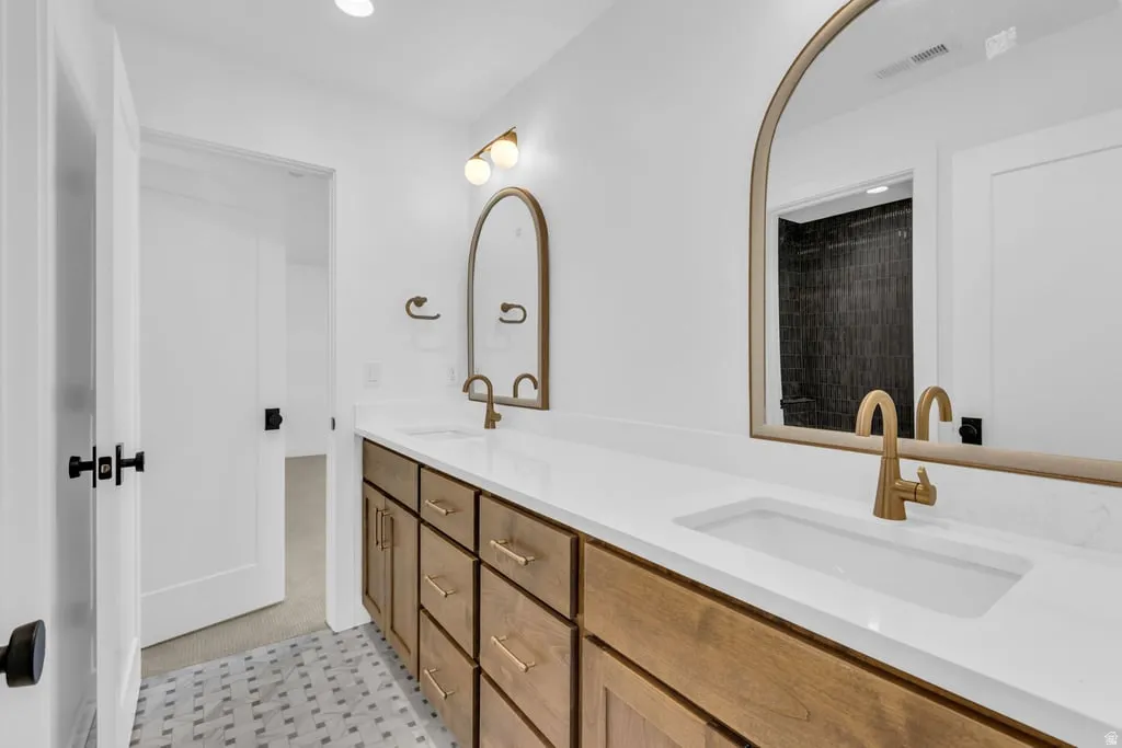 Double vanity featuring white countertops, undermount sinks, and brass-finish hardware