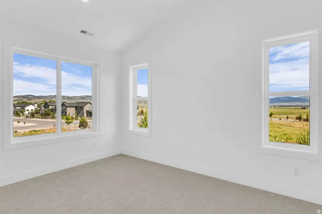 Spacious room featuring multiple windows, recessed ceiling lighting, and light-toned carpeting