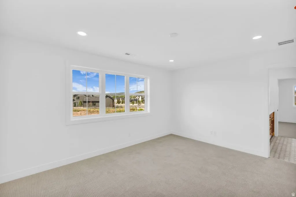 Bright interior space featuring a multi-pane window, recessed lighting, and light-toned carpeting