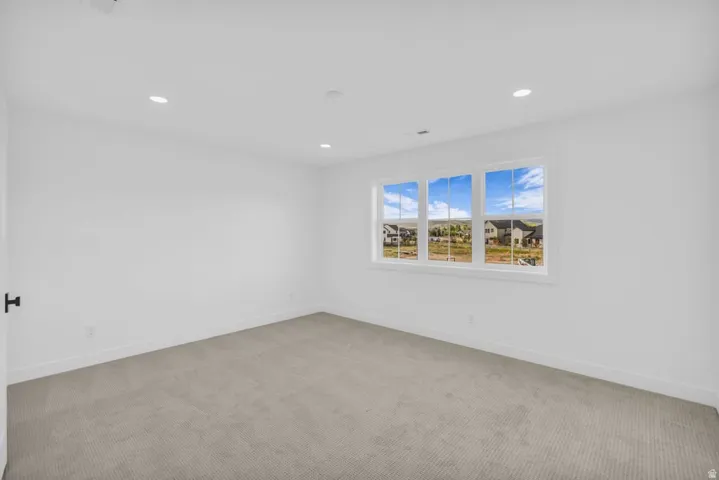 Bright room featuring crisp white walls, recessed lighting, a triple window, and neutral carpeting