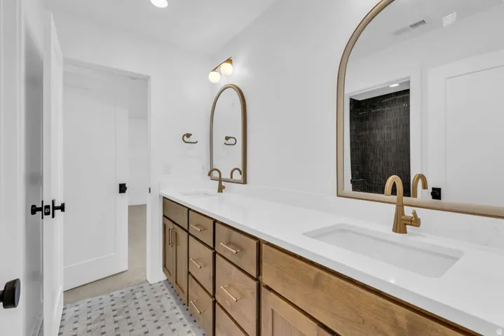 Double vanity featuring white countertops, undermount sinks, and brass-finish hardware
