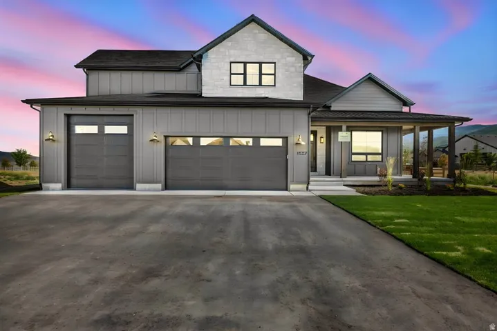 Modern farmhouse exterior featuring gray vertical siding and light-toned stone accents