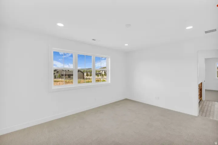 Bright interior space featuring a multi-pane window, recessed lighting, and light-toned carpeting