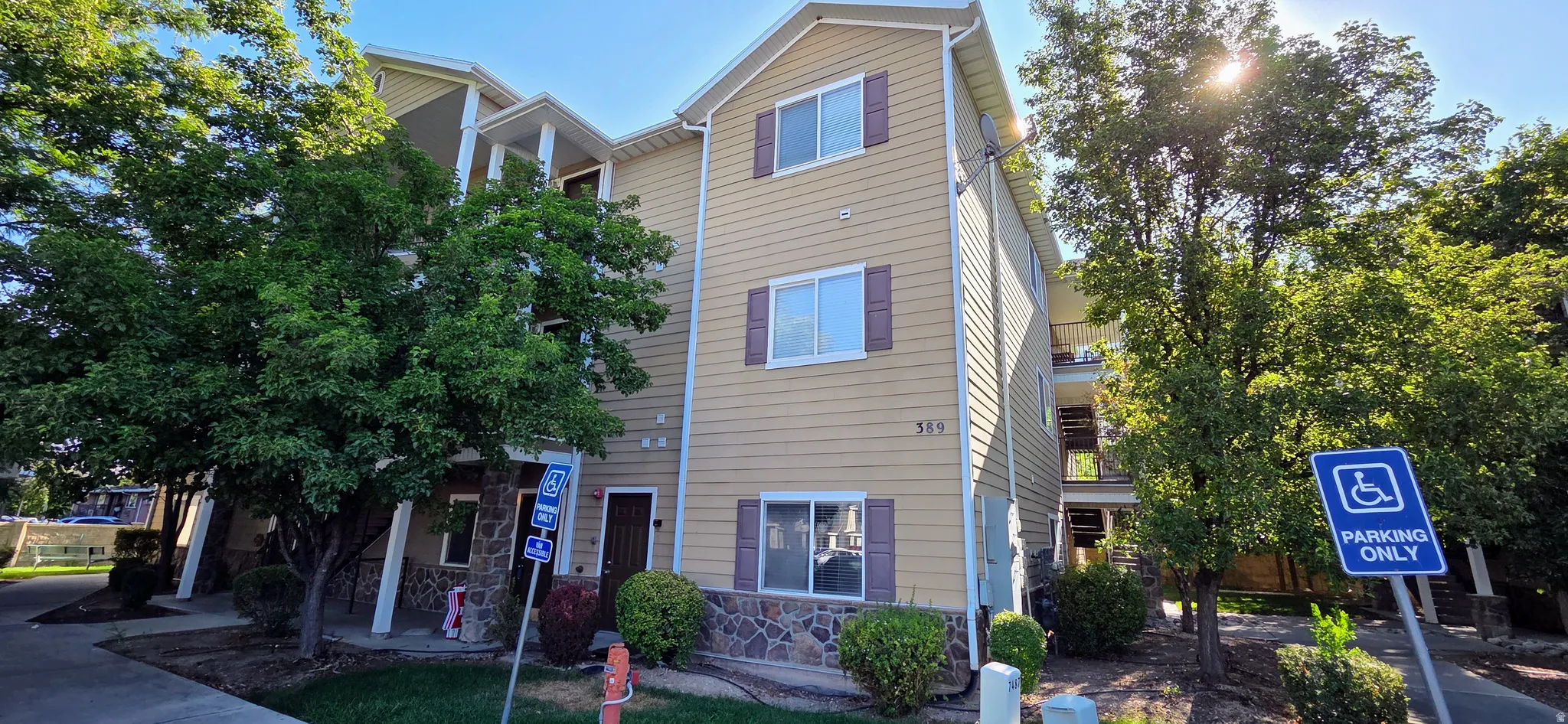 Three-story building with tan siding and stone veneer accents