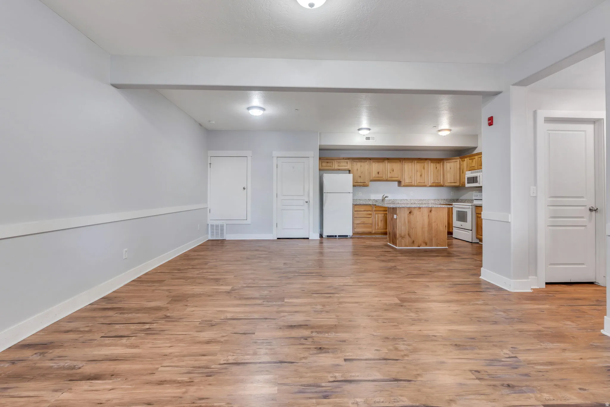Expansive open-concept living area featuring wood-finish flooring, recessed lighting, and a full kitchen