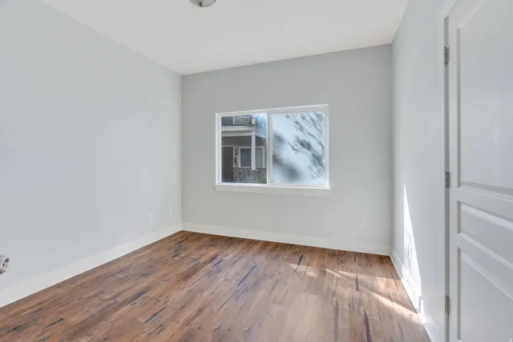 Wood-finish flooring, white trim, recessed window, and a paneled interior door
