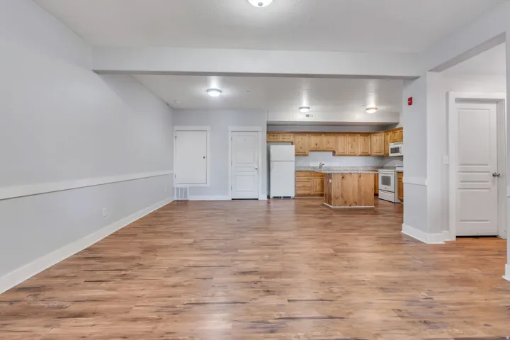 Expansive open-concept living area featuring wood-finish flooring, recessed lighting, and a full kitchen